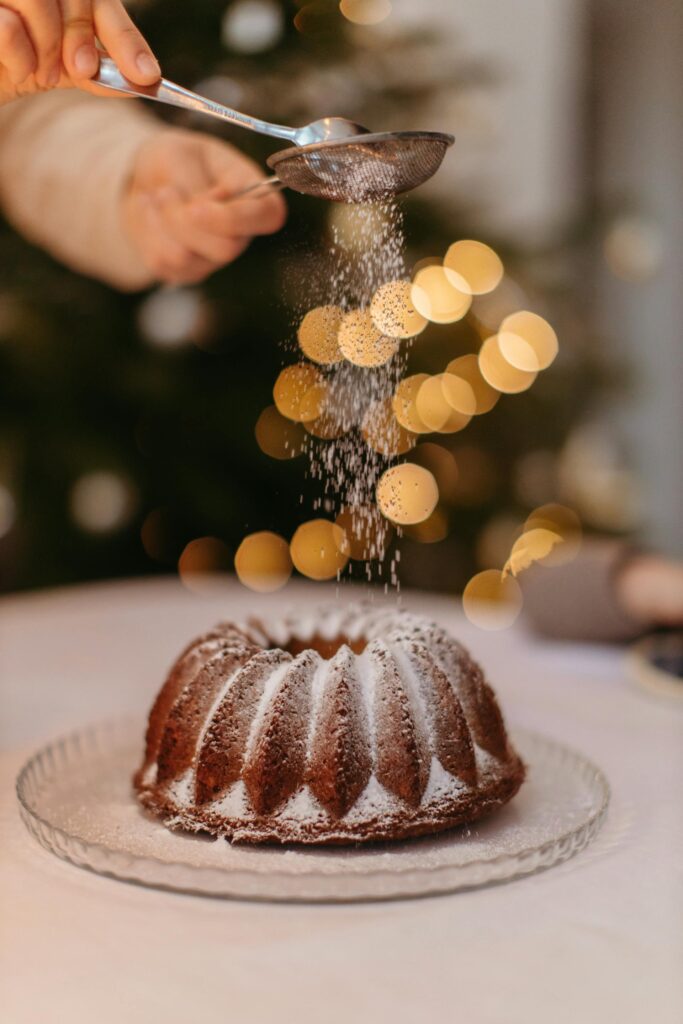 Espolvoreando azúcar glass sobre un pastel tipo Bundt cake para decoración final