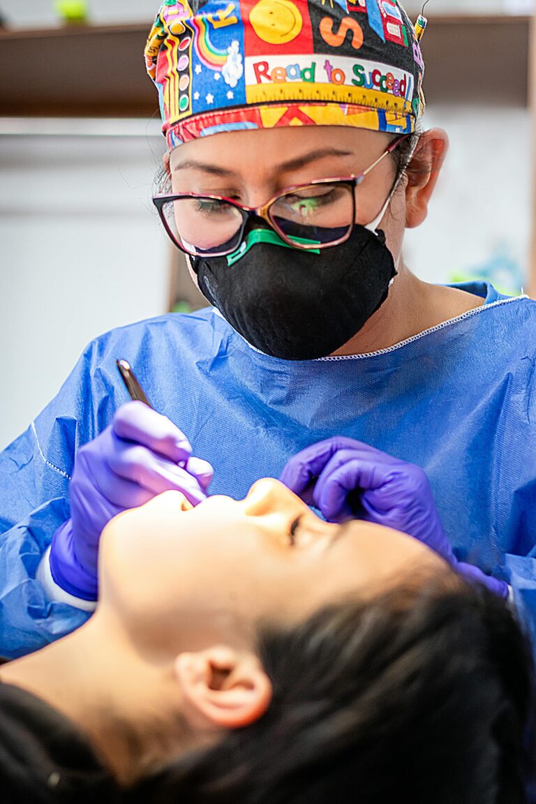 Profesional odontólogo con mascarillas y gafas de protectoras atendiendo a un paciente reclinado