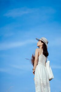 Mujer usando sombrero de ala gris y vestido blanco sin mangas