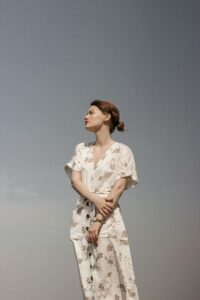 Mujer de perfil luciendo un vestido midi blanco con estampado floral sutil y mangas cortas