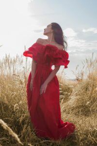 Mujer usando vestido largo rojo intenso con hombros descubiertos y volantes