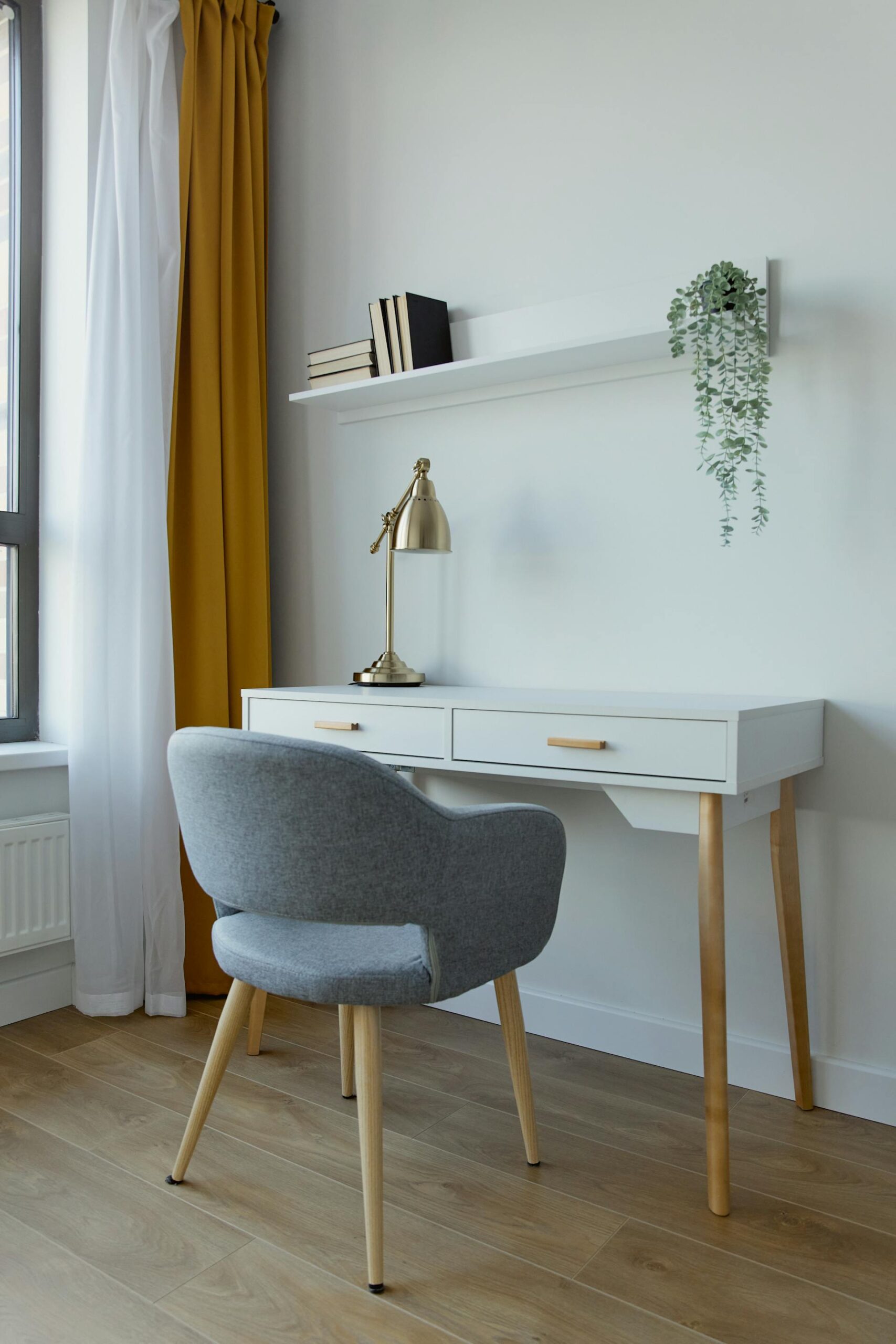 Espacio de trabajo minimalista con escritorio blanco, silla gris tapizada y estante flotante
