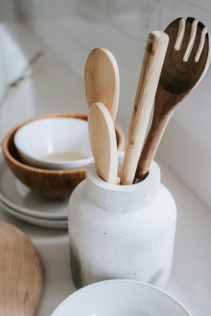 Cuchara y espátula de cocina de madera dentro de un tarro de cerámica