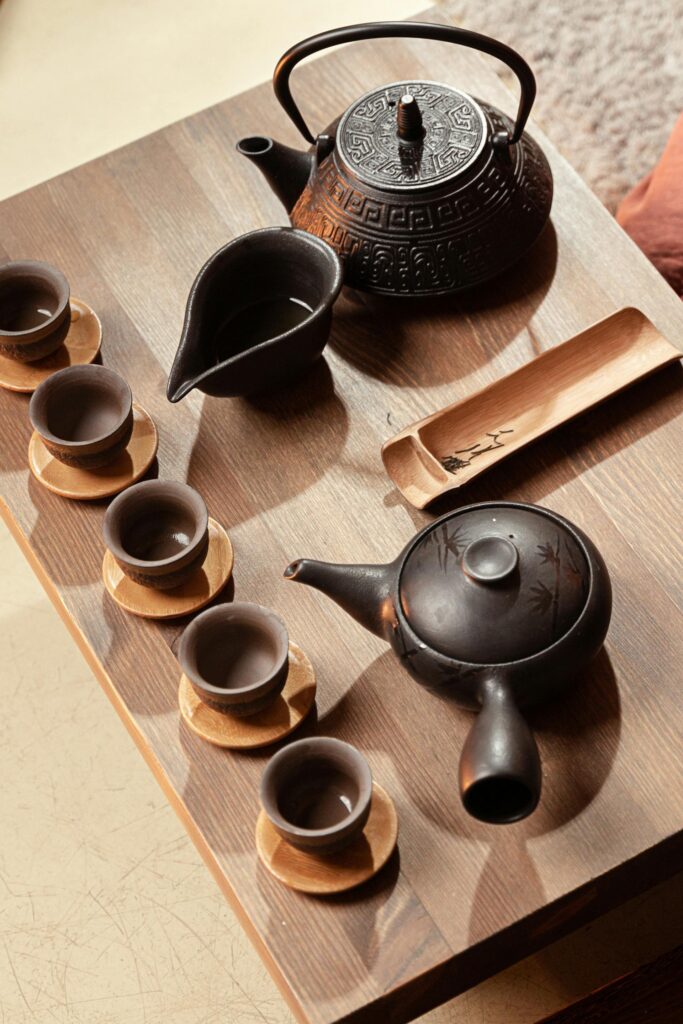 Set de tetera y cuencos de cerámica oscura sobre bandeja de madera