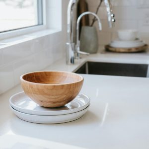 Cuenco de madera sobre platos de cerámica blanca