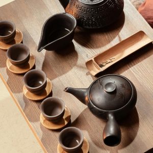 Set de tetera y cuencos de cerámica oscura sobre bandeja de madera