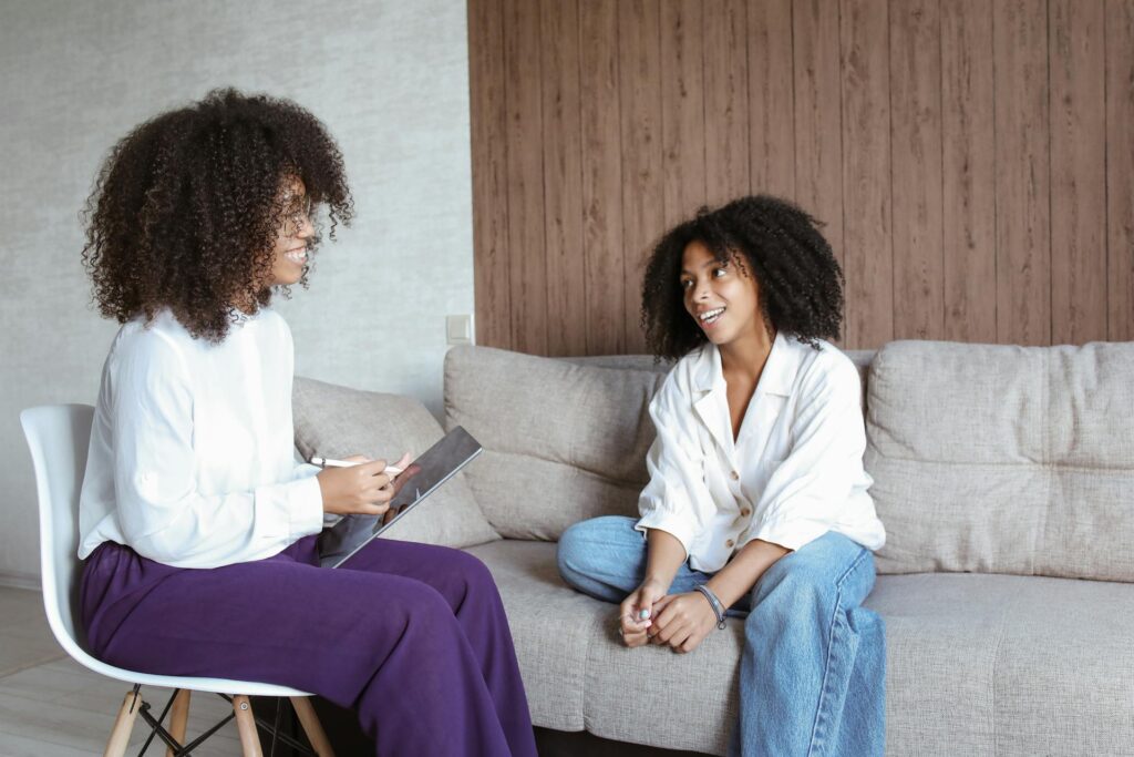 Dos mujeres sentadas en un sofá conversando en un ambiente relajado