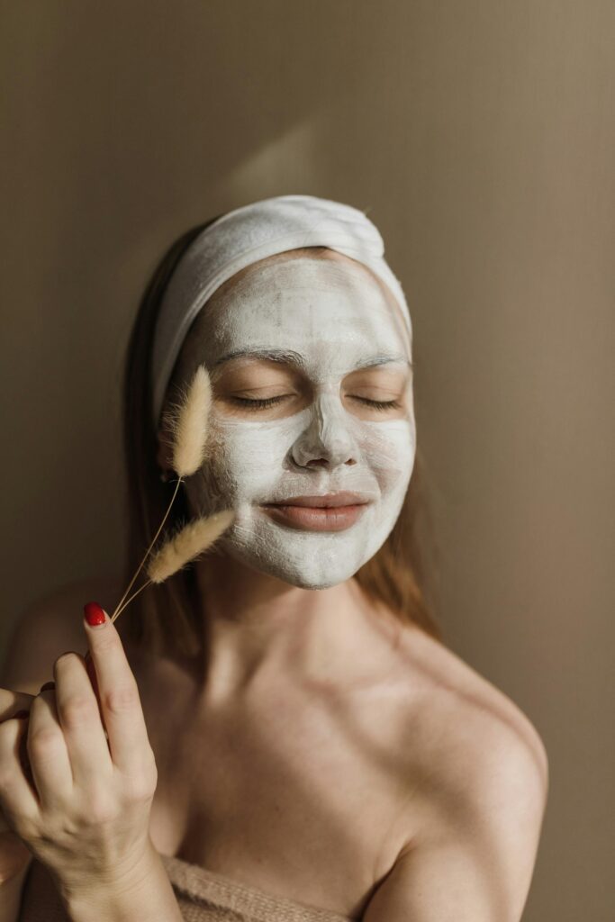 Mujer relajada con una toalla en la cabeza y mascarilla facial de arcilla blanca aplicada