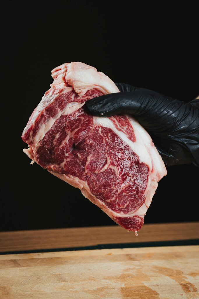 Carnicero sosteniendo un corte fresco de Ribeye con alto marmoleo