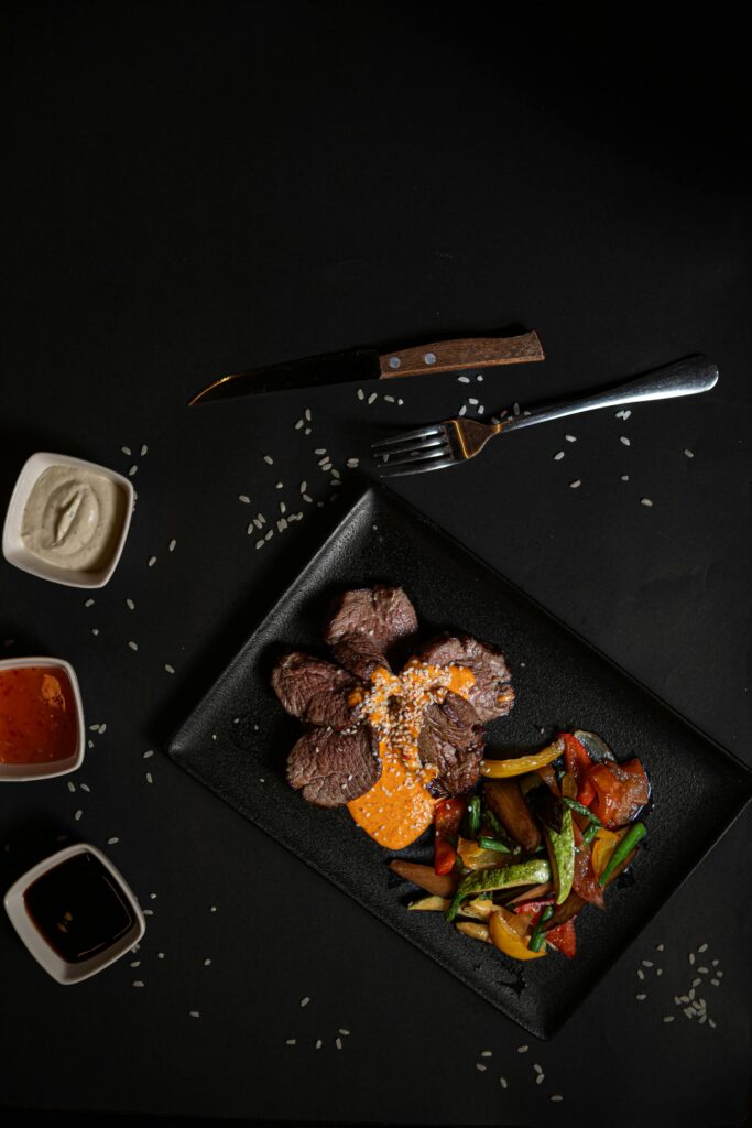 Cubos de carne asada presentados elegantemente en plato oscuro para degustación