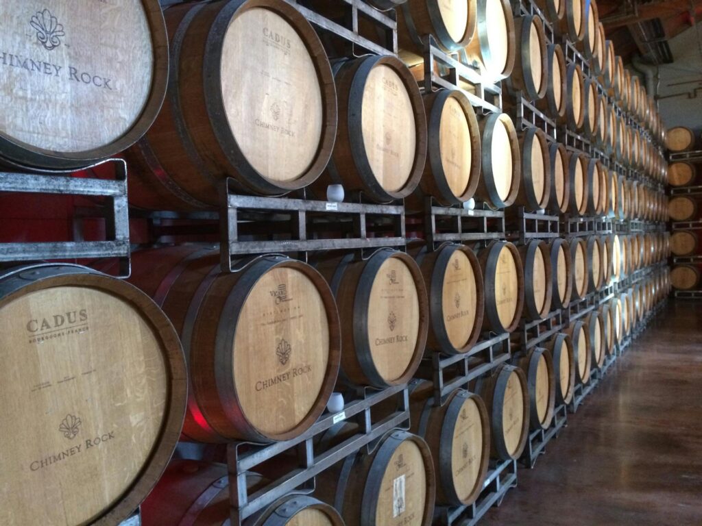 Pared de barriles de vino de madera apilados en filas dentro de una bodega de envejecimiento