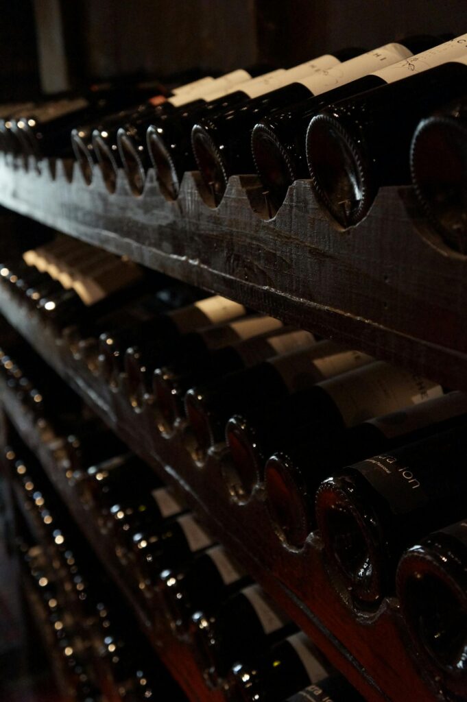 Primer plano en ángulo de botellas de vino almacenadas horizontalmente en una estantería de madera oscuro