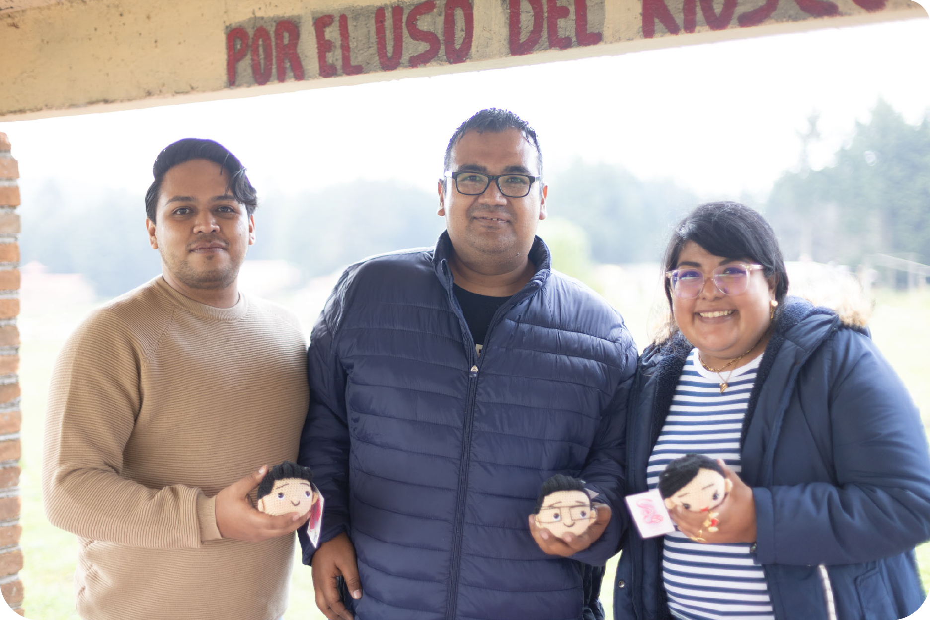 Miembros del equipo mostrando sus regalos personalizados: figuras de croché hechas a su imagen y semejanza durante un evento de integración.