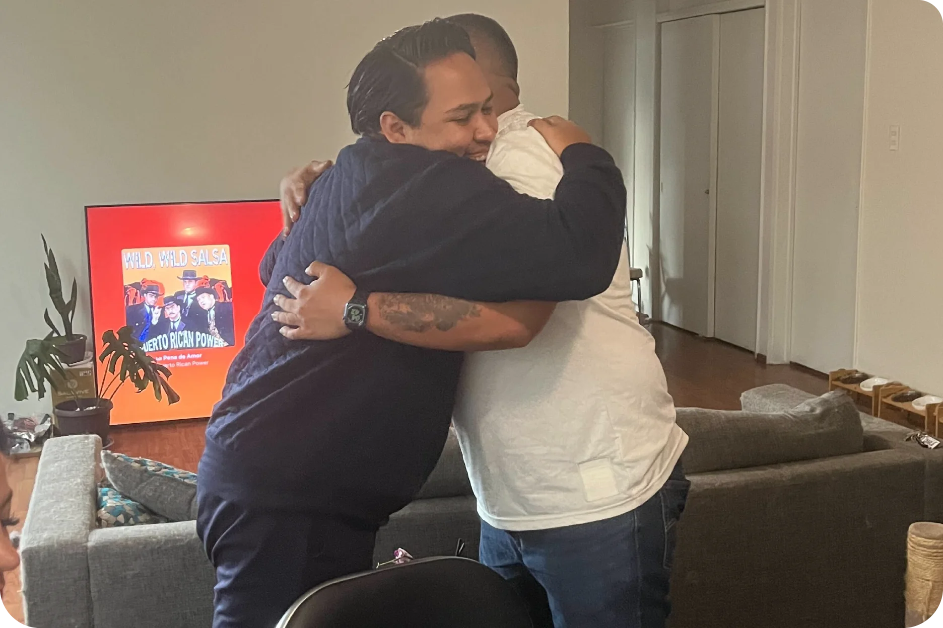 Un momento emotivo de amistad y celebración entre dos compañeros durante una reunión social informal.