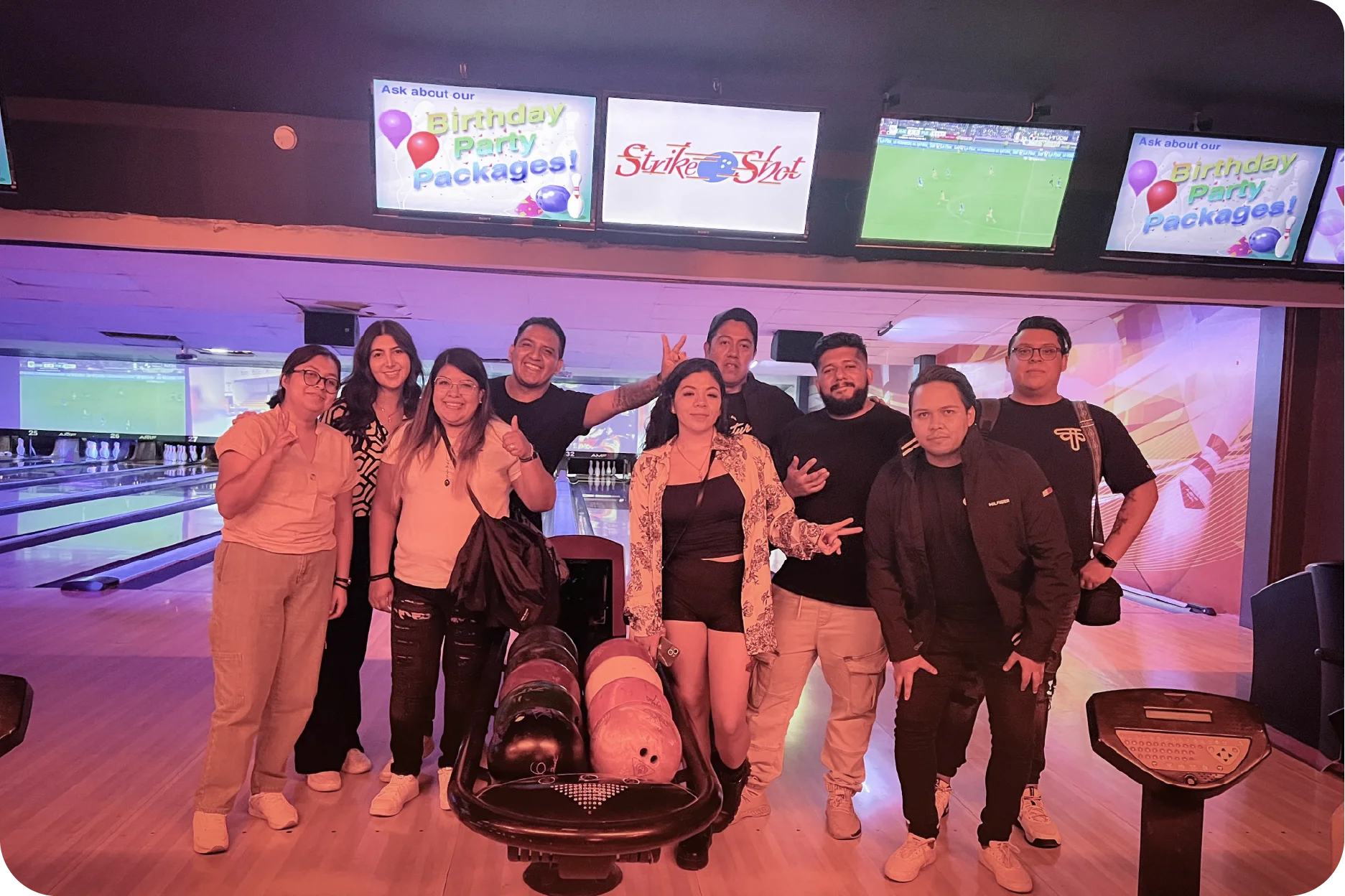 Foto grupal del equipo de trabajo celebrando y divirtiéndose durante una noche de integración en el boliche.